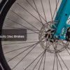 Close-up view of the Soltera 2.5 Ebike's front wheel with hydraulic disc brakes and a turquoise fork.
