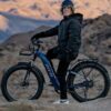 A man is standing on an AVENTURE.2 Step Through Ebike in the desert.