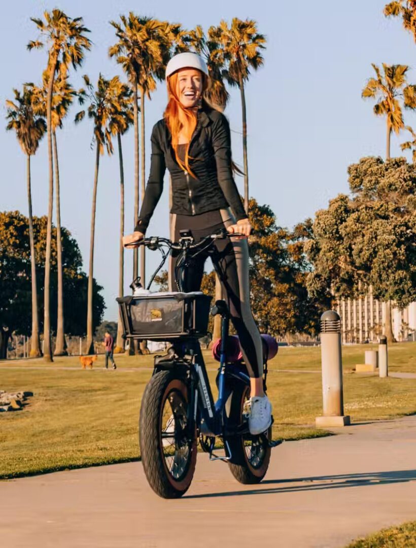 A woman riding an electric bike in front of palm trees in the USA.