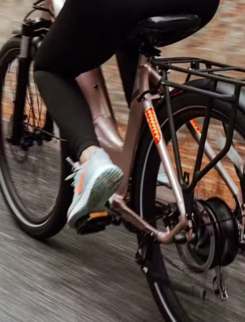 A woman is riding an electric bike down a street in the USA.