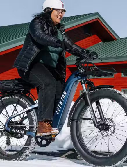 A woman riding a fat bike in the snow, showcasing Ebikes accessories.