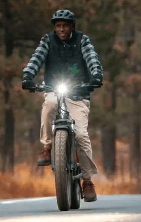 A man riding an electric bike in the woods, equipped with e-bike accessories.