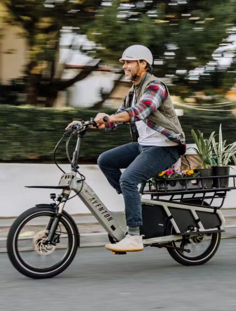 A man riding an electric bike with a basket full of plants, showcasing the benefits of ebikes and e-bikes accessories.