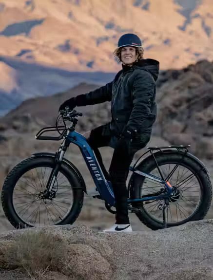 A man standing next to a fat bike in the desert, showcasing e-bike accessories in WA, USA.