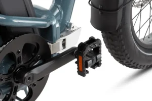 Close-up of an electric bike showing the crankset, pedal, and part of the rear wheel with a thick tire.