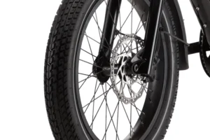 Close-up of a bicycle's front wheel featuring a disc brake system with thick tread on the tire and black spokes.