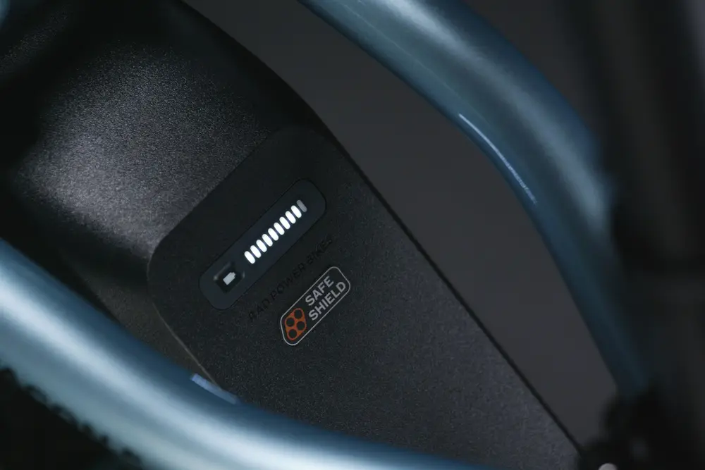 Close-up view of a dark-colored electronic device displaying an LED indicator and a "Safe Shield" sticker.