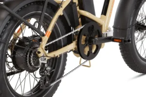 Close-up view of a beige electric bicycle's rear wheel and drivetrain, showing its chain, gears, and motor.