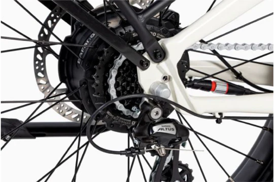 Close-up view of a bicycle gear system featuring Shimano Altus components and a disc brake. The chain, derailleur, and spokes are visible against a white bike frame.