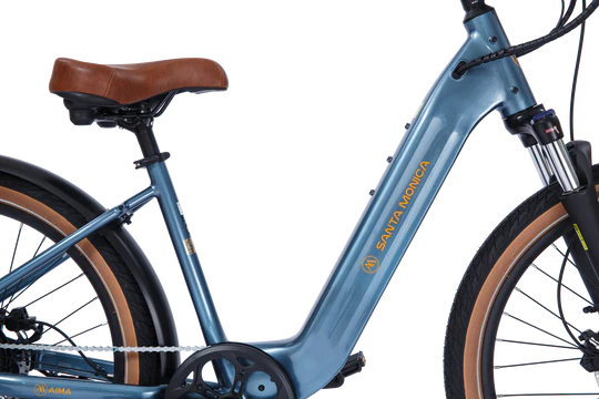 A blue electric bicycle with brown leather seat and tan wheels, featuring the words "SANTA MONICA" on the frame.