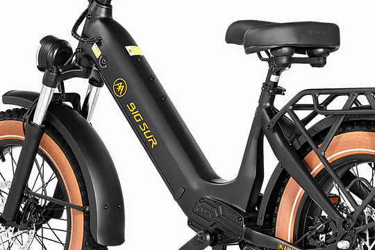 Close-up of a black electric bicycle with "Big Sur" branding on the frame, featuring a step-through design, front suspension fork, and rear cargo rack.