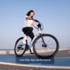 Person riding a bicycle on a seaside road with the text "Low step, high performance.