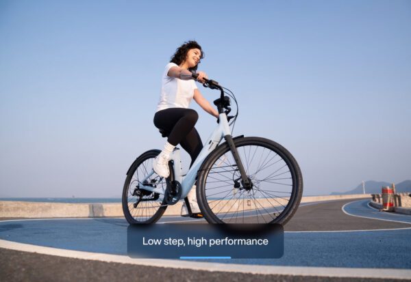 Person riding a bicycle on a seaside road with the text "Low step, high performance.