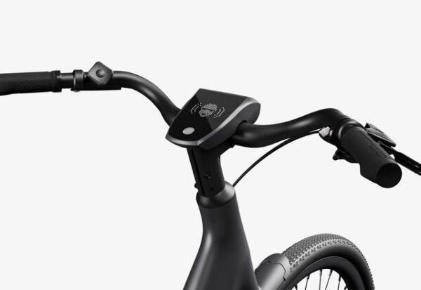 The image shows a close-up of bicycle handlebars with a control panel mounted in the center. The grip and brake system is visible on either side.