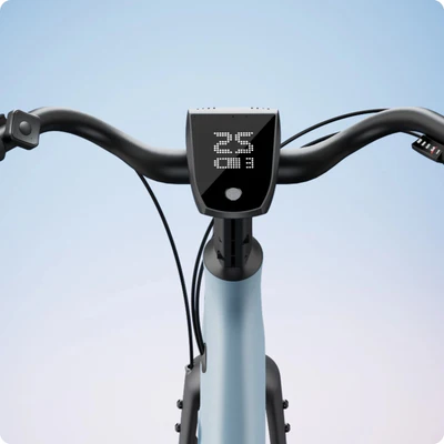 Close-up of bicycle handlebars with a digital display showing parts of a number on a light blue background.