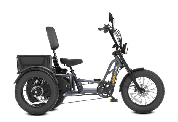 The Meet One Tour Lite Full Suspension Electric Trike is a three-wheeled electric bike featuring a large cushioned seat, wide tires, rear cargo box, and upright handlebars, shown in a side view.