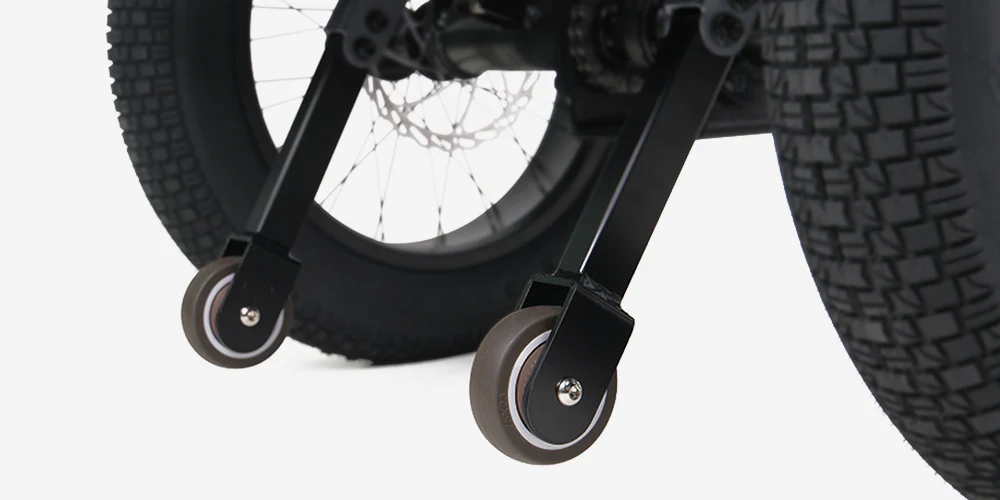 Close-up of two small training wheels attached to the rear of a bicycle with large, knobby tires.