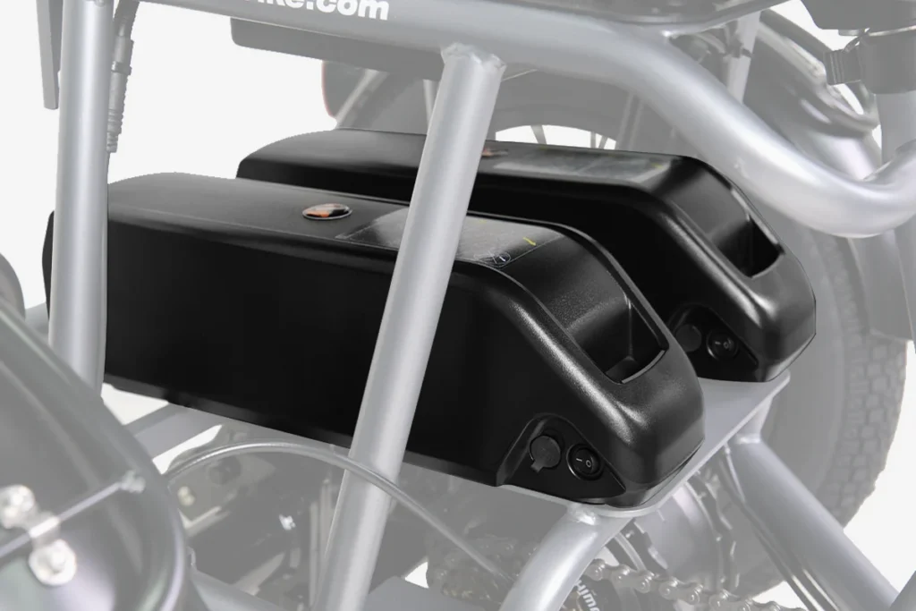 Two black battery packs mounted on a metal frame, positioned side by side, with part of a wheel visible in the background.