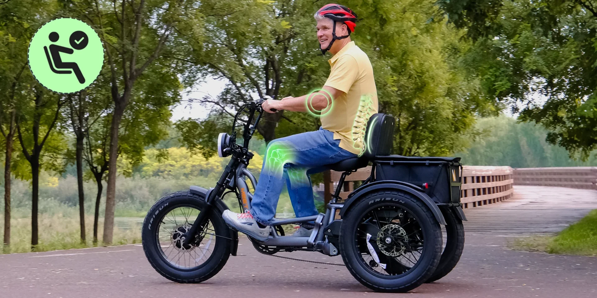 A man wearing a red helmet rides an adaptive electric tricycle on a park path; a green accessibility icon appears in the corner.
