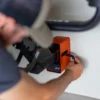 Someone uses a key to lock or unlock the Rack Dock, a wall-mounted box, while holding a large item in their other hand near the device.