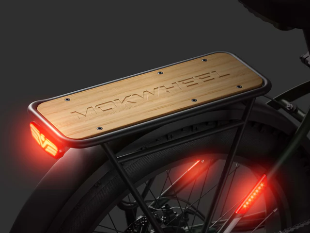 Rear view of an electric bike featuring a bamboo cargo rack labeled "MOKWHEEL," with illuminated rear lights and a dark background.