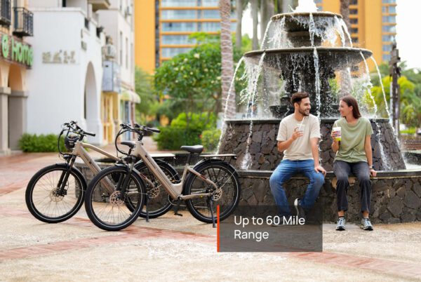 Two people relax next to a stone fountain with three Asphalt Ebikes parked nearby; a text overlay reads, "Up to 60 Mile Range.