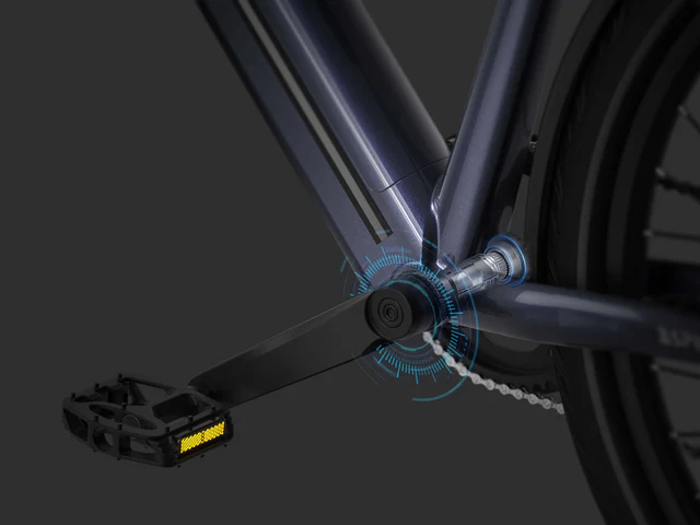 Close-up of a bicycle crank arm, pedal, and chain, with a digital graphic overlay highlighting the pedal axle area, suggesting a focus on technology or sensors.