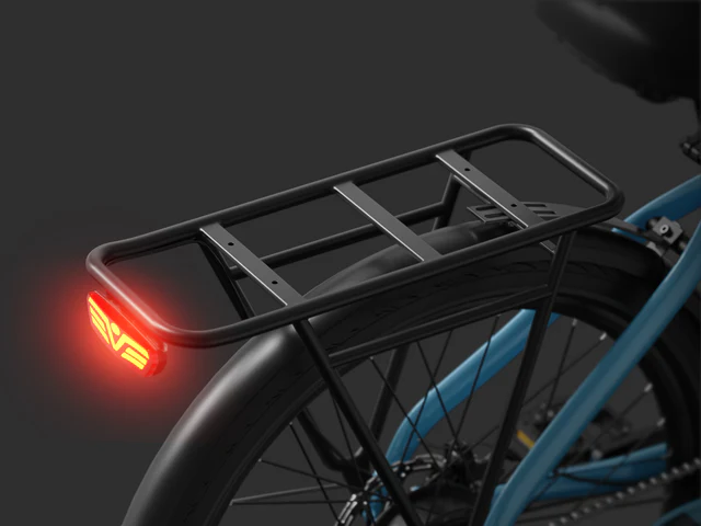 Black metal bicycle rear rack mounted above the back wheel, with a red LED tail light illuminated on the left side.