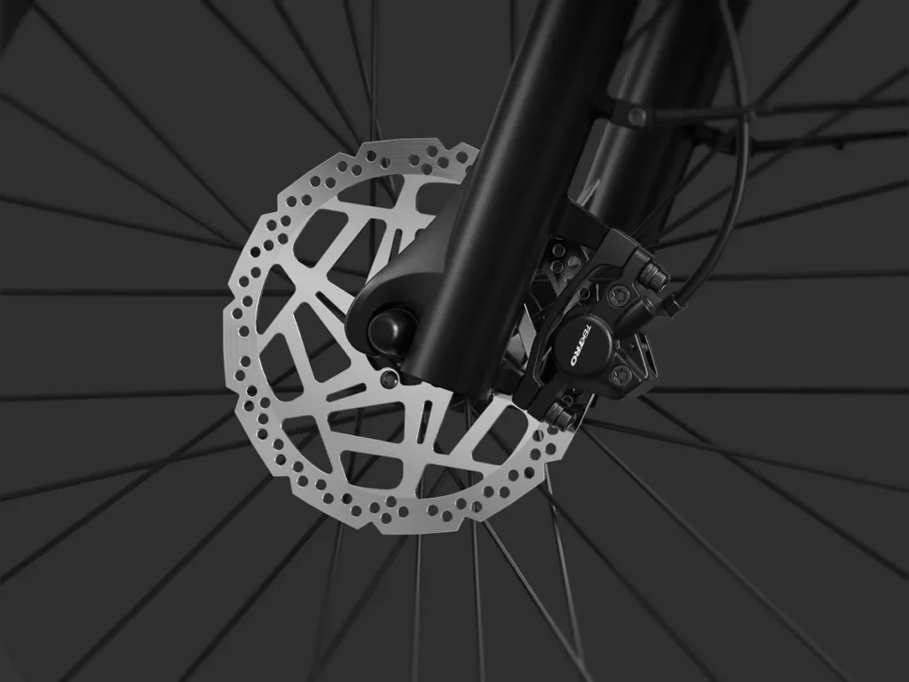 Close-up view of a bicycle disc brake system, showing the rotor, caliper, and spokes against a dark background.