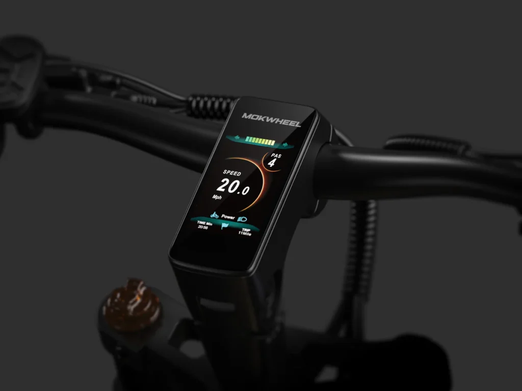 Close-up view of an e-bike handlebar with a digital display showing speed, power, and battery status; the display reads 20.0 kph and is branded "Mokwheel.
