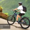 A person wearing a helmet and backpack rides the Tarmac ST Ebike downhill near a lake, with text overlay: "Torque+Cadence Sensor".