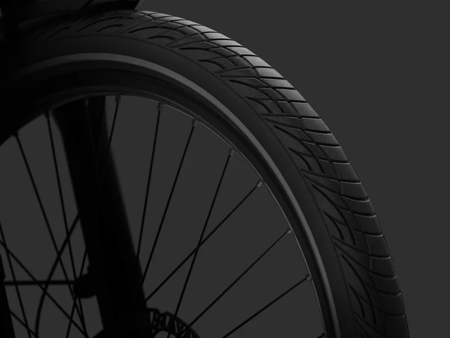 Close-up of a bicycle wheel showing the tire tread, rim, and spokes against a dark background.