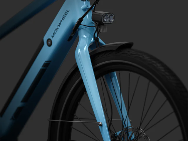 Close-up of a blue Mokwheel bicycle’s front fork, headlight, and tire against a dark background.