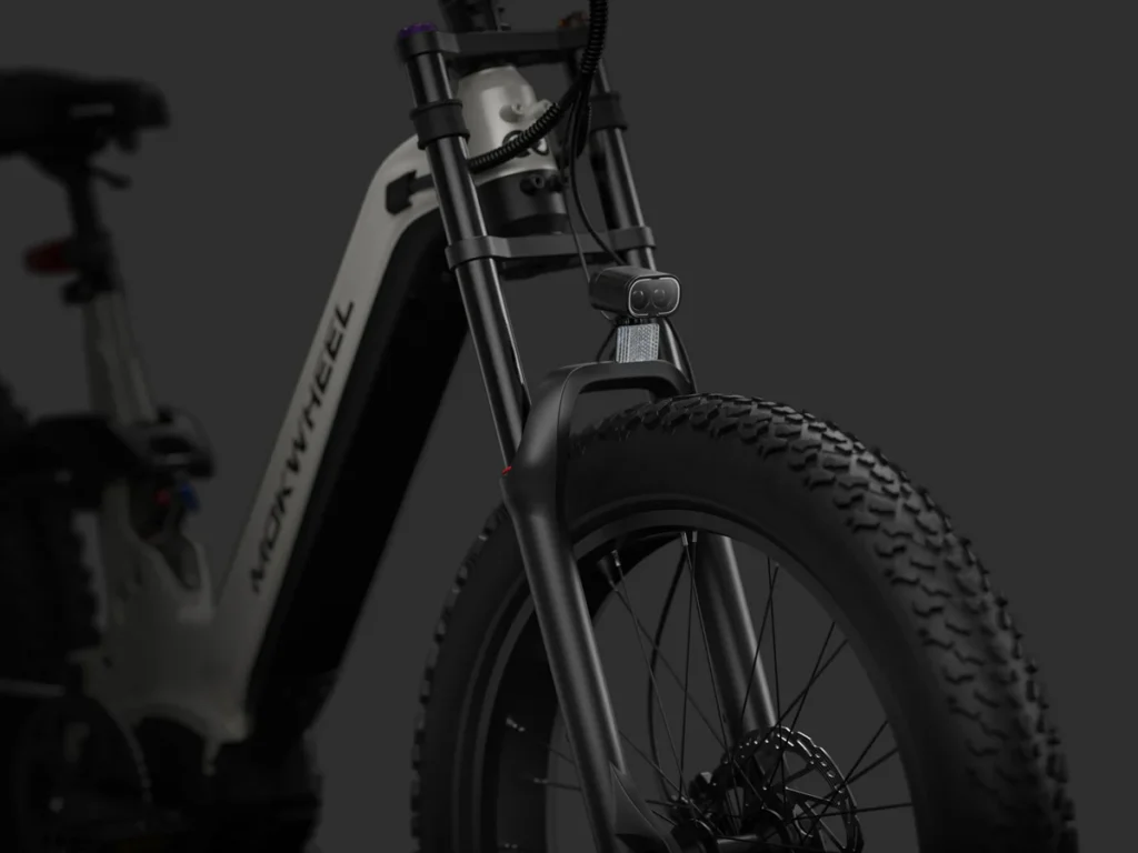 Close-up of the front suspension, wheel, and frame of a black electric bike against a dark background.