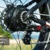Close-up of the Obsidian ST Ebike's rear wheel featuring the Shimano 8-speed gear system, chain, cassette, and derailleur, set against a blurred outdoor background.