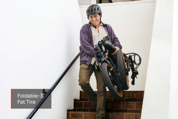 A person wearing a helmet carries a folded Slate Ebike with 3'' fat tires down stairs. Text overlay: "Foldable-3'' Fat Tire.