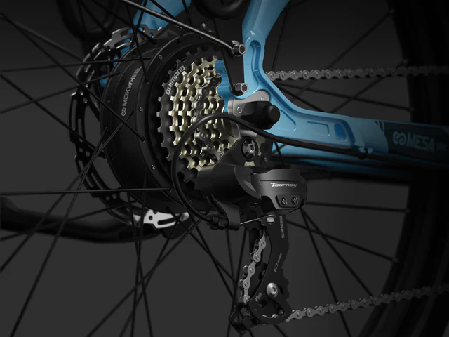 Close-up of a bicycle's rear derailleur, cassette, and chain on a blue frame, showing the gear system and mechanical components.