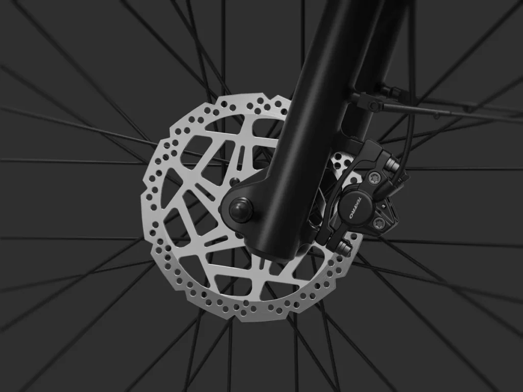 Close-up view of a bicycle front wheel featuring a disc brake rotor and caliper against a dark background.