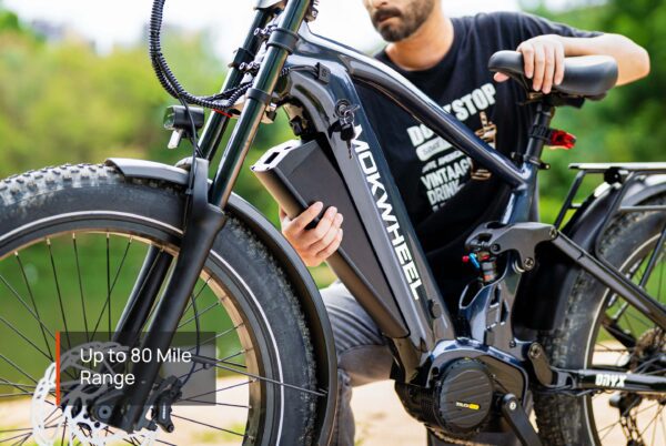 A person removes the battery from a black Onyx Ebike outdoors. Text overlay reads, "Up to 80 Mile Range.