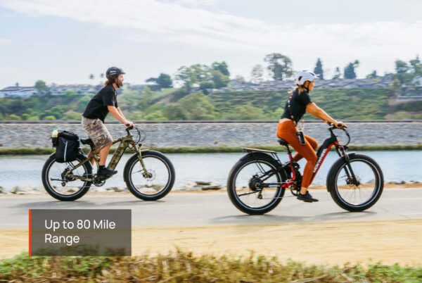 Two people ride Obsidian ST Ebikes on a paved riverside path, with a caption overlay stating "Up to 80 Mile Range.