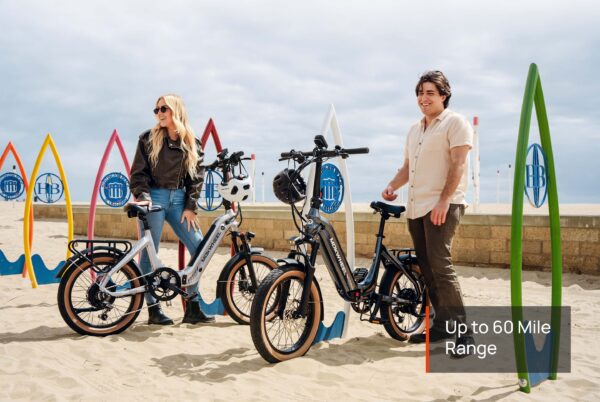 Two people with Slate Ebikes stand on a sandy beach near colorful surfboard-shaped bike racks. Text reads: "Slate Ebike – Up to 60 Mile Range.