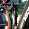 Close-up of a DNM full suspension shock absorber on a black Obsidian Ebike, with the frame and rear tire visible in the background.
