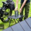 A Basalt ST 2.0 Ebike sits outdoors beside a table where a portable power station connects to a foldable solar panel. Text: "Inverter Compatible.