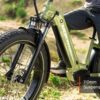 Close-up of a person on a Basalt ST 2.0 Ebike in olive green with thick tires, featuring a front fork labeled "110mm Suspension Fork.