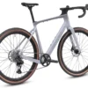 The CF Racer1 is a modern gravel bike featuring a light gray frame, drop handlebars, disc brakes, and tan-walled tires, displayed from a rear-side angle on a white background.