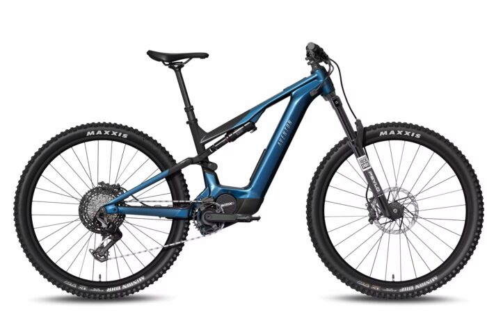 The Current ADV Ebike is a blue full-suspension electric mountain bike featuring large Maxxis-branded knobby tires, disc brakes, and a mid-drive motor.