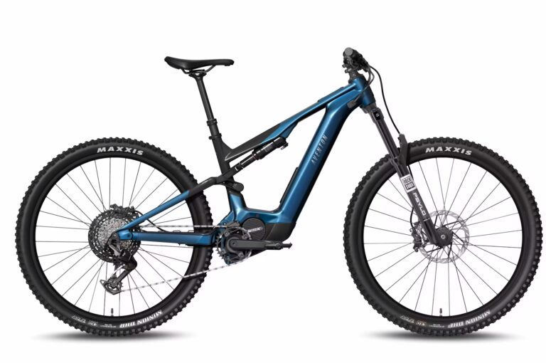 The Current ADV Ebike is a blue full-suspension electric mountain bike featuring large Maxxis-branded knobby tires, disc brakes, and a mid-drive motor.