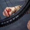 A person checks the air pressure of a Maxxis mountain bike tire using a red gauge.