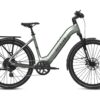 Aventon step-through electric commuter bike in sage green, featuring a rear rack, fenders, and disc brakes.