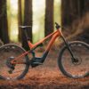 Orange and black Aventon electric mountain bike parked on a forest floor.